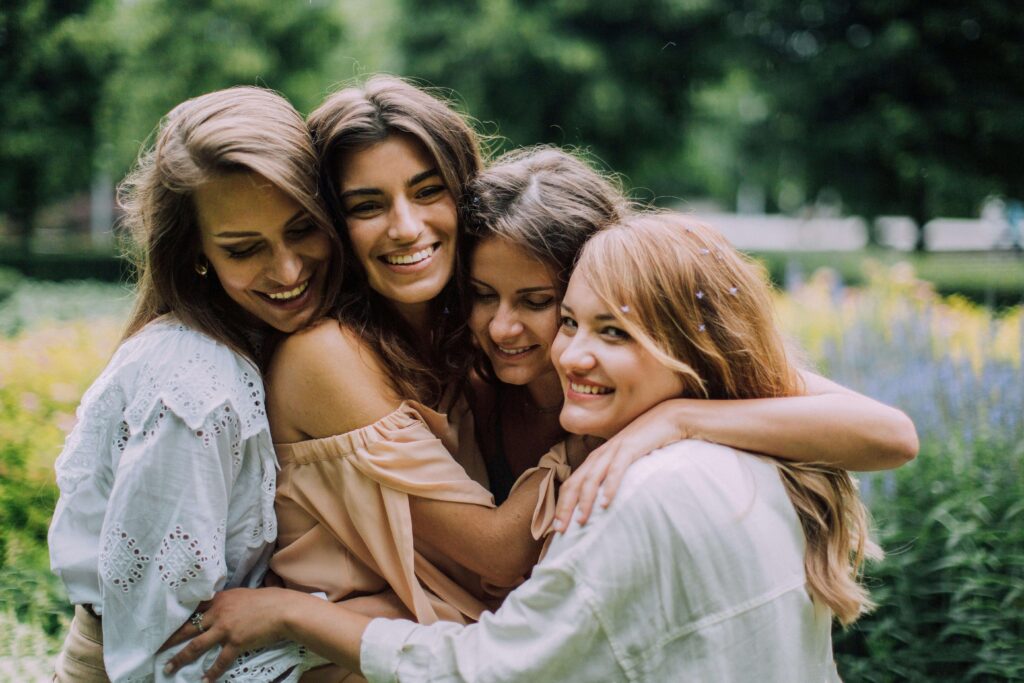 A group of four friends embracing and smiling outdoors, reflecting authentic connection and supportive relationships. Begin healing from within and improve your relationships with the support of relationship therapy in Los Angeles, CA.