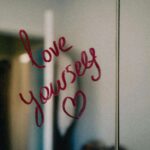 A mirror with “Love yourself” written in red lipstick, symbolizing self-compassion and the importance of nurturing your relationship with yourself. Learn to embrace your relationship with yourself with the support of relationship therapy in Los Angeles, CA.
