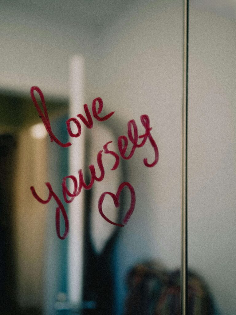 A mirror with “Love yourself” written in red lipstick, symbolizing self-compassion and the importance of nurturing your relationship with yourself. Learn to embrace your relationship with yourself with the support of relationship therapy in Los Angeles, CA.