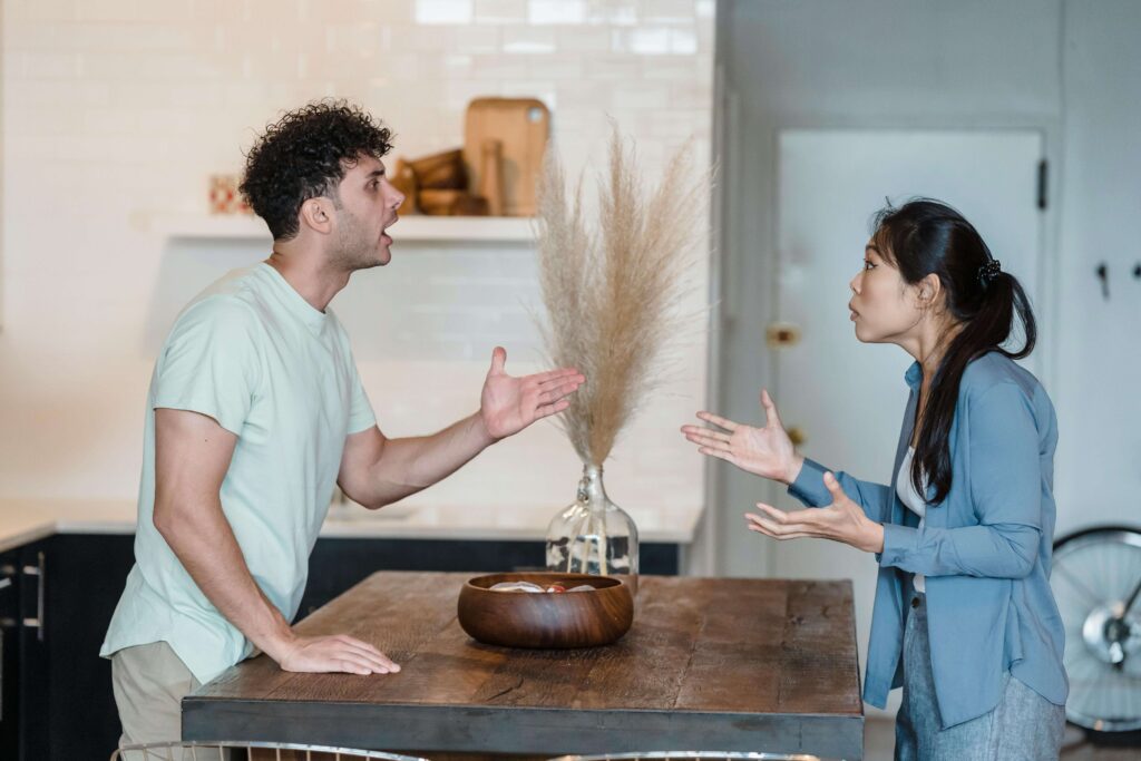 A couple stands on opposite sides of a kitchen island, raising their voices during an argument, expressing frustration and miscommunication. With the support of a relationship therapist in Los Angeles, CA you can begin to heal from the anger in your relationship.
