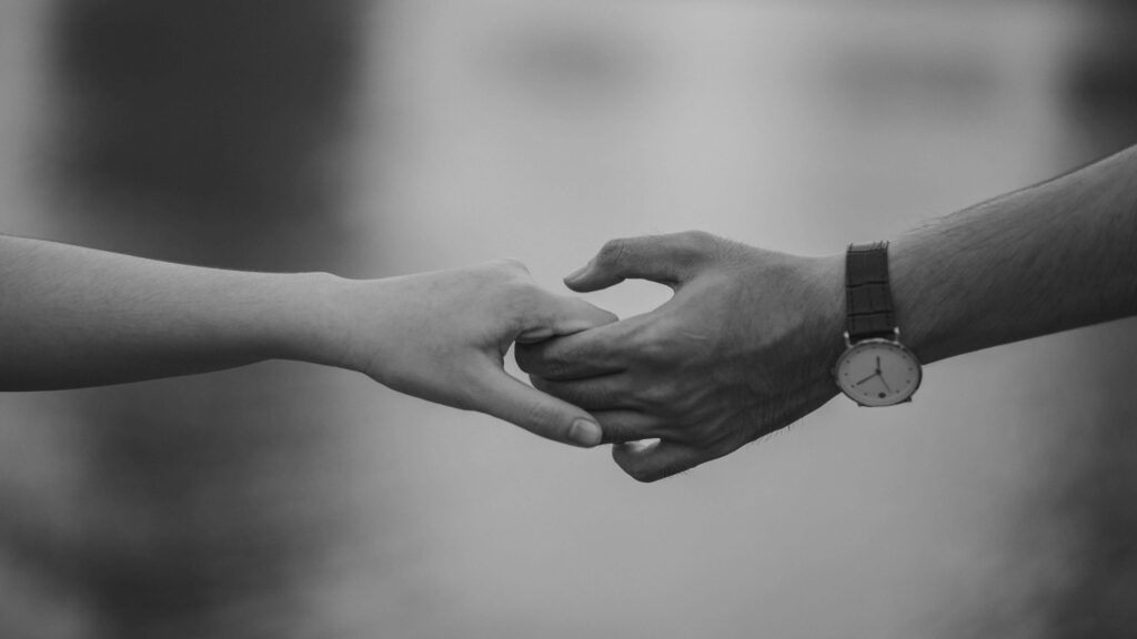 holding hands | relationship therapy in los angeles, ca | healthy boundaries in relationships | boundaries in relationships | Encino | Tarzana | Sherman Oaks Two people reaching toward each other and gently holding hands in a black-and-white photograph. Relationship therapy in Los Angeles, CA can help you build boundaries that support connection without overextending.