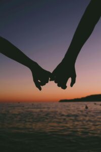 Silhouette of a couple holding hands at sunset over the ocean, symbolizing emotional connection and unity. Rediscover emotional softness and deeper connection through relationship therapy in Los Angeles, CA with support from a compassionate relationship therapist.