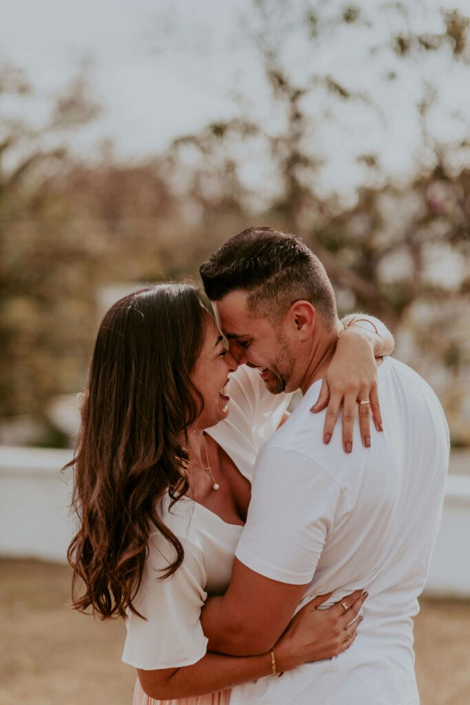 Couple standing close together outdoors, smiling and embracing with their foreheads touching. By fostering understanding and emotional safety, relationship therapy in Los Angeles, CA helps couples move forward together.