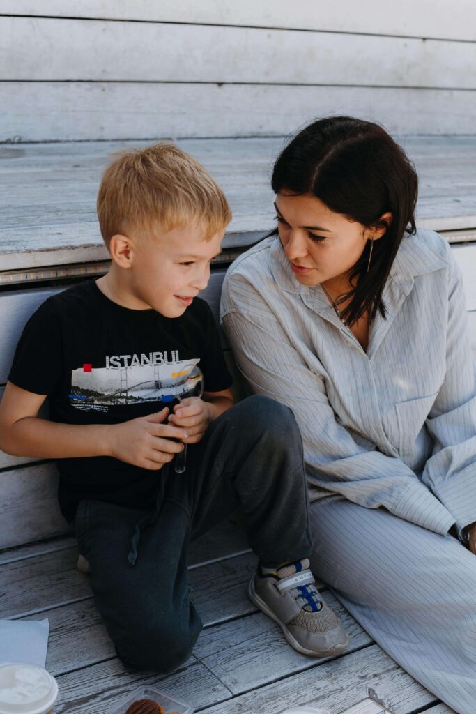 Mother sitting with young son on wooden deck having a conversation. Break reactive patterns and create grounded connection through relationship therapy in Los Angeles, CA.