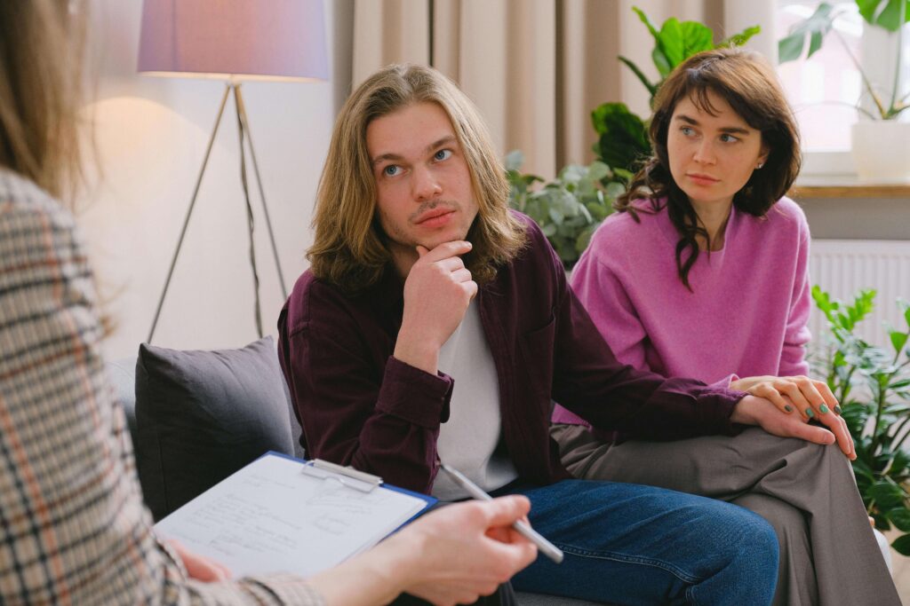 Couple sitting on couch listening to therapist during counseling session. Learn to express honestly without fear in a structured space through relationship therapy in Los Angeles, CA.