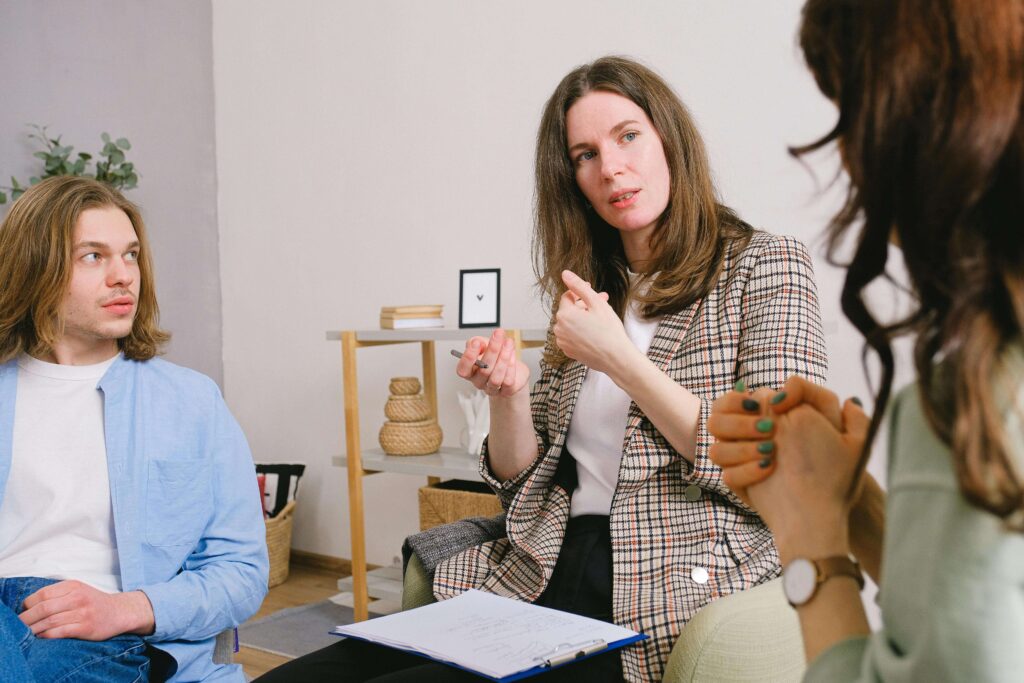 Therapist in plaid blazer gesturing while speaking to couple in session. Discover what your anger is protecting in a safe space through relationship therapy in Los Angeles, CA.