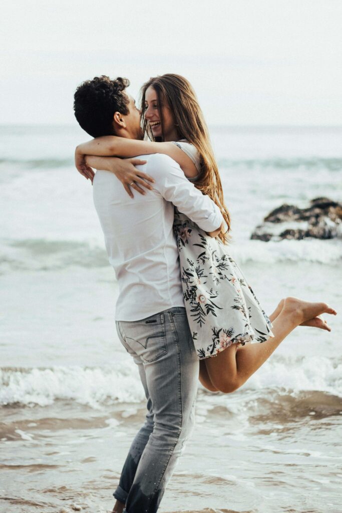 Couple embracing joyfully at the beach with ocean in background. Self-intimacy creates the foundation for authentic connection with relationship therapy in Los Angeles, CA.