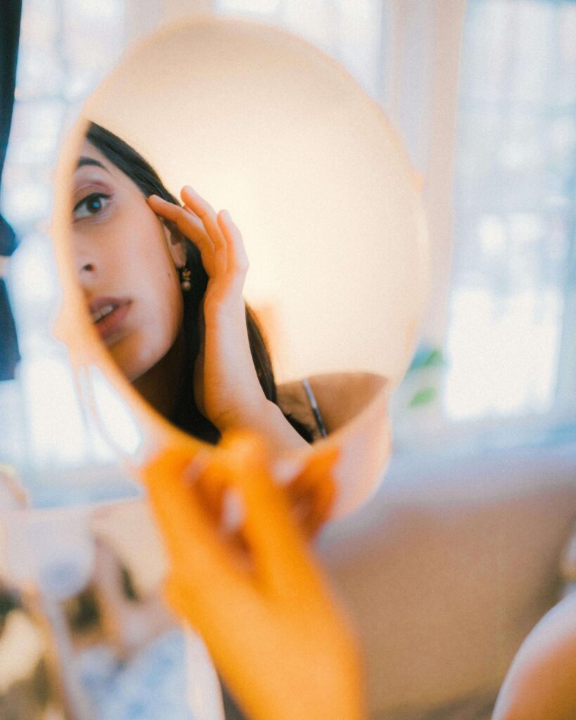 mirror reflection | self love in Los Angeles, CA | relationship therapy | loving yourself | West Hills | Agoura Hills | Sherman Oaks Woman looking at herself in round mirror with hand on face. Develop honest contact with your own experience through relationship therapy in Los Angeles, CA.