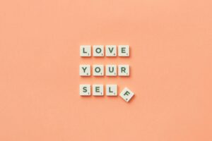 Scrabble tiles spelling out "love yourself" on peach background. Build the relationship with yourself that transforms how you love through relationship therapy in Los Angeles, CA.