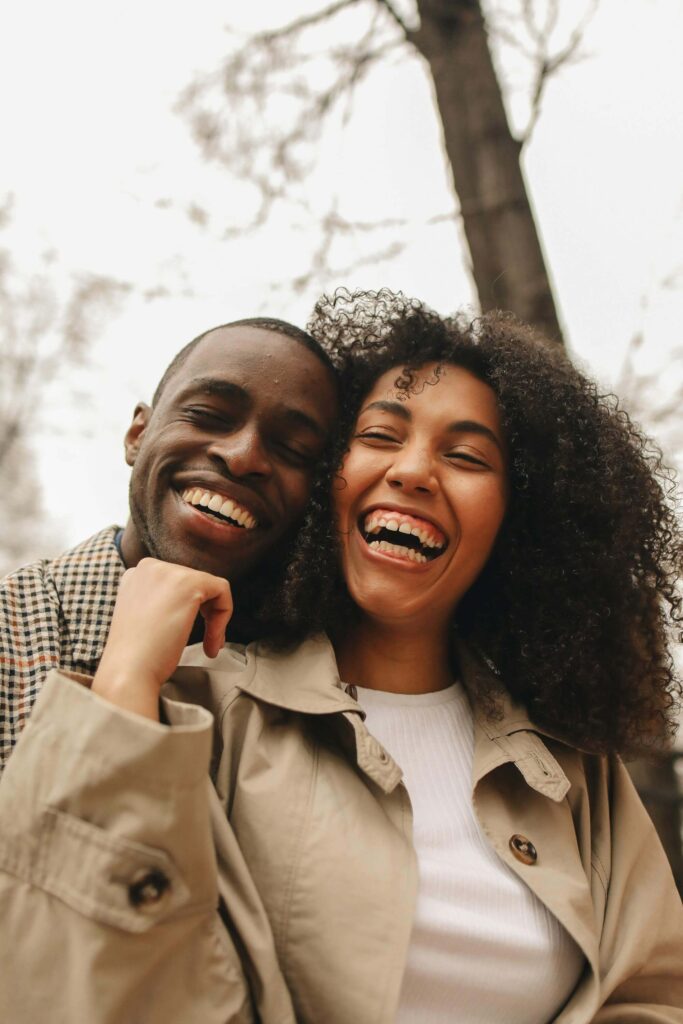 Couple laughing together outdoors with tree in background. Discover how boundaries strengthen connection, not weaken it, through relationship therapy in Los Angeles, CA.