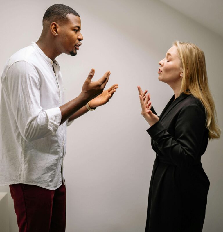 Couple having intense conversation with hands gesturing facing each other. Understand what your conflicts are really revealing through relationship therapy in Los Angeles, CA.